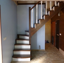 Г-образная (с поворотом 90°) деревянная лестница. Пригласительная ступень. Заход без ограждений, после поворота перила с точёными балясиными, крашенными в контрастный белый цвет. Материал- сосна.
