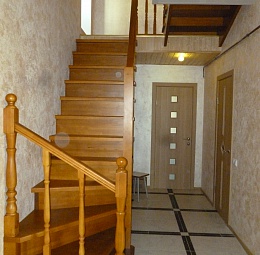 Комбинированная деревянная лестница: снизу забежные ступени, в середине большая площадка. Материал - сосна, лестница затонирована в светлый тон, залакирована.