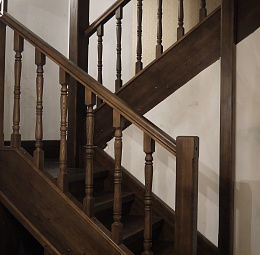 Поворотная (п-образная) деревянная лестница с площадкой между этажами. Ступени прямые. Материал - лиственница, тонированная морилкой. Точёные симметричные балясины.